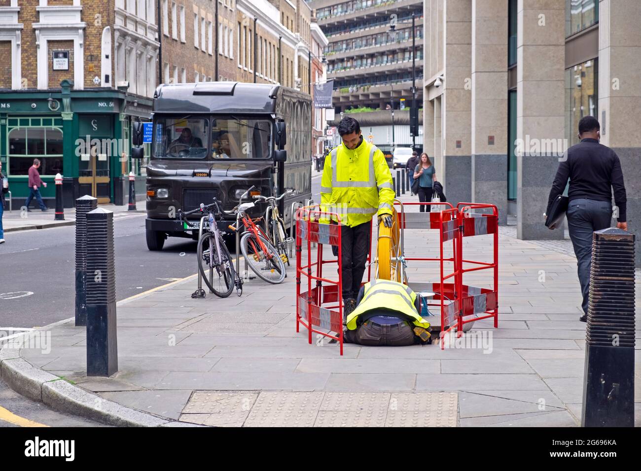 Arbeiter mit gelben fluoreszierenden Jacken arbeiten in einem Schachtloch in der Chiswell Street London EC2 England UK KATHY DEWITT Stockfoto