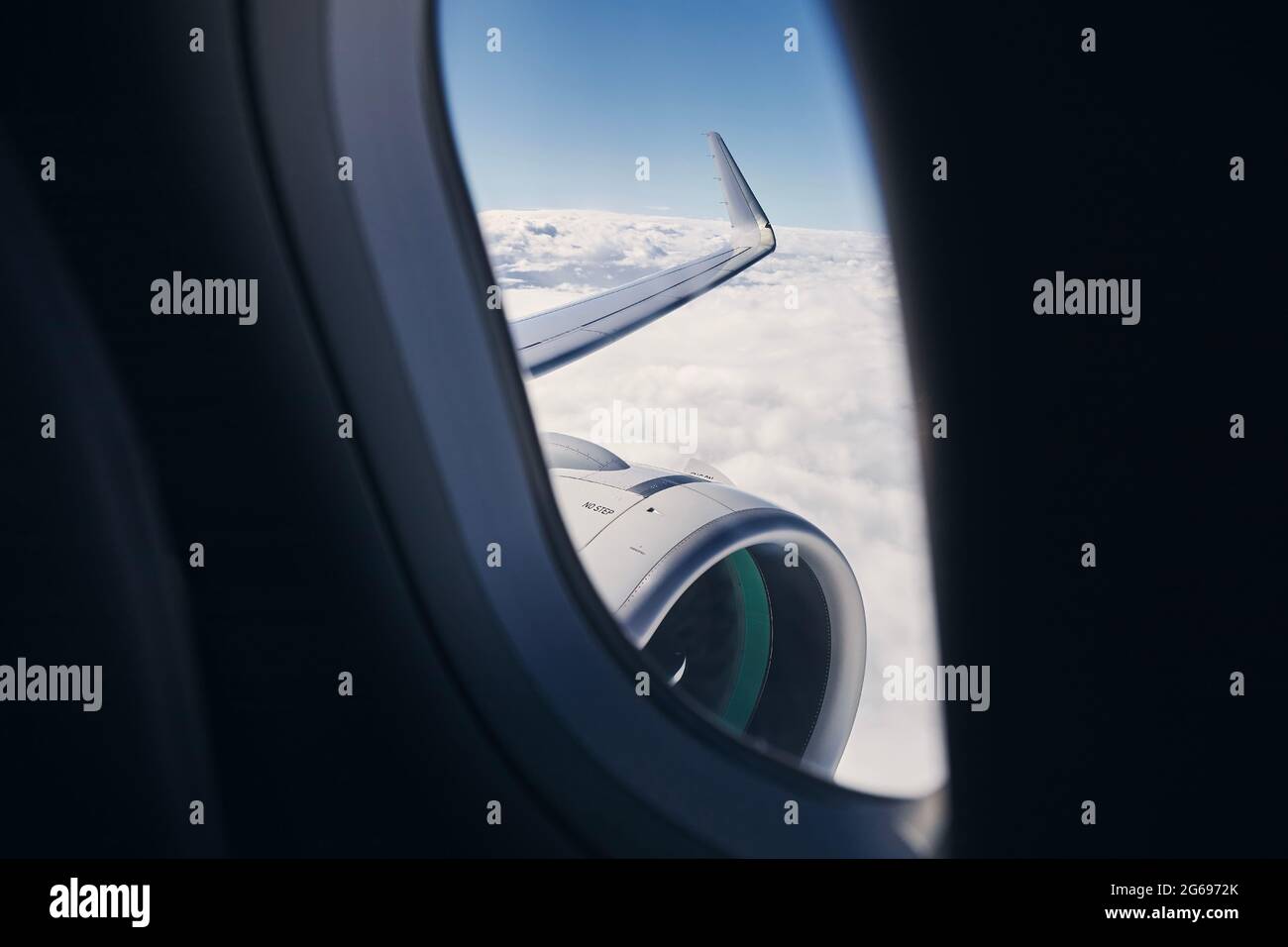 Blick durch das Flugzeugfenster auf Flügel mit Motor. Flugzeug während des Fluges über Wolken. Stockfoto