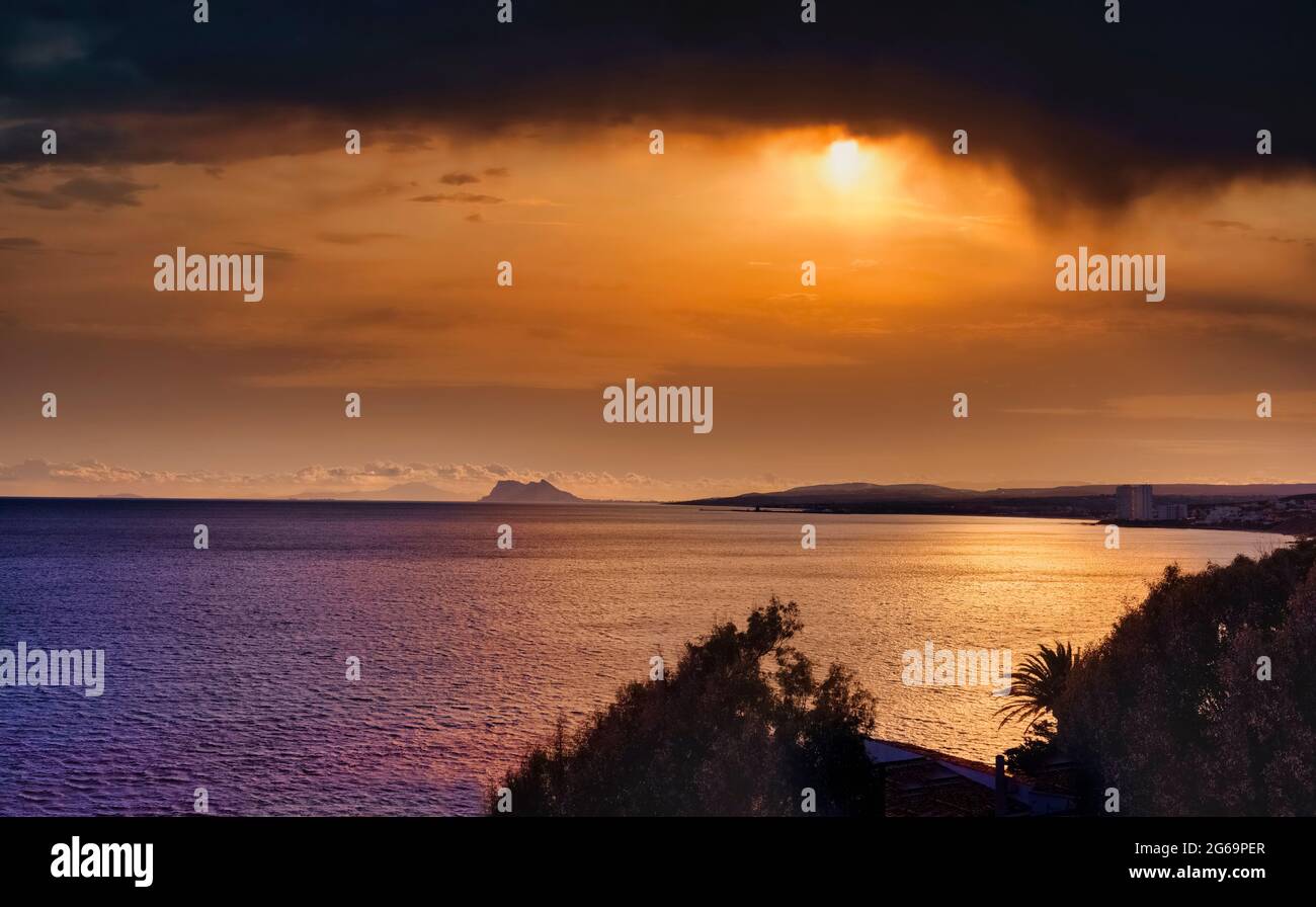 Gibraltar (Zentrum) und Marokko (hinten) bei Sonnenuntergang von Playa de la Chullera, Manilva, Costa del Sol, Provinz Malaga, Andalusien, Spanien. Stockfoto