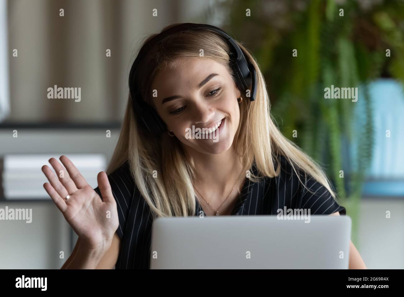 Nahaufnahme einer Geschäftsfrau mit Kopfhörern, die Hand an der Webcam des Laptops schwenkt Stockfoto
