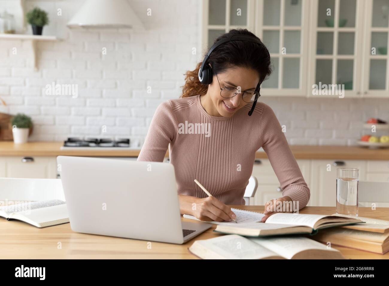Lächelnde junge Frau, die an Online-Bildung beteiligt ist. Stockfoto