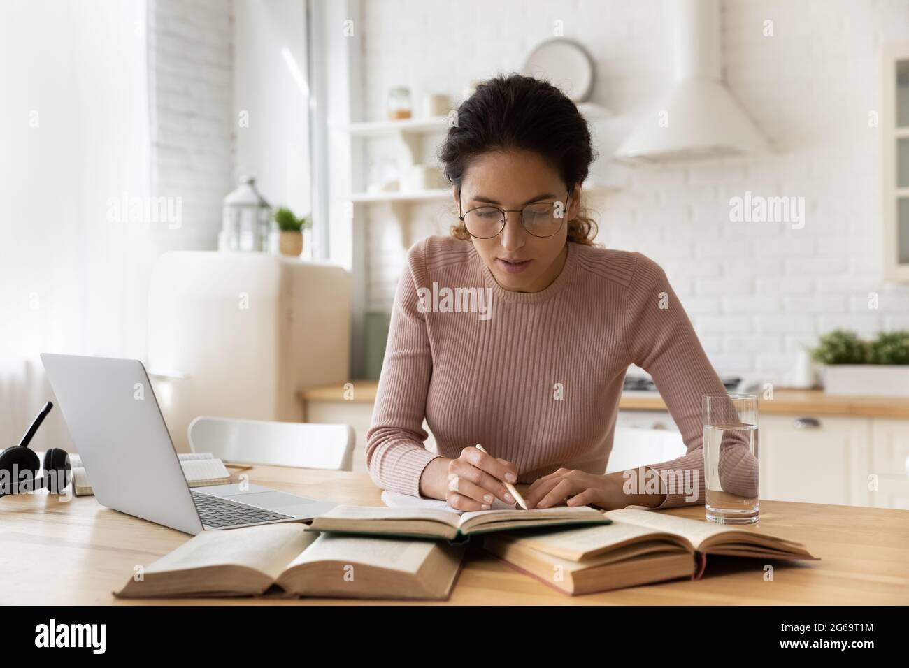 Konzentrierte junge Frau in der Brille beim Lesen des Lehrbuches. Stockfoto