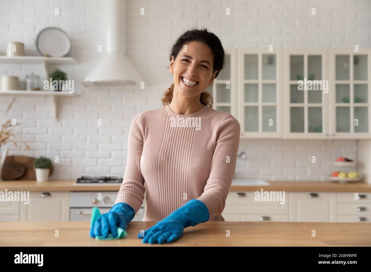 Portrait der lächelnden hispanischen Hausfrau Reinigung der Küche. Stockfoto