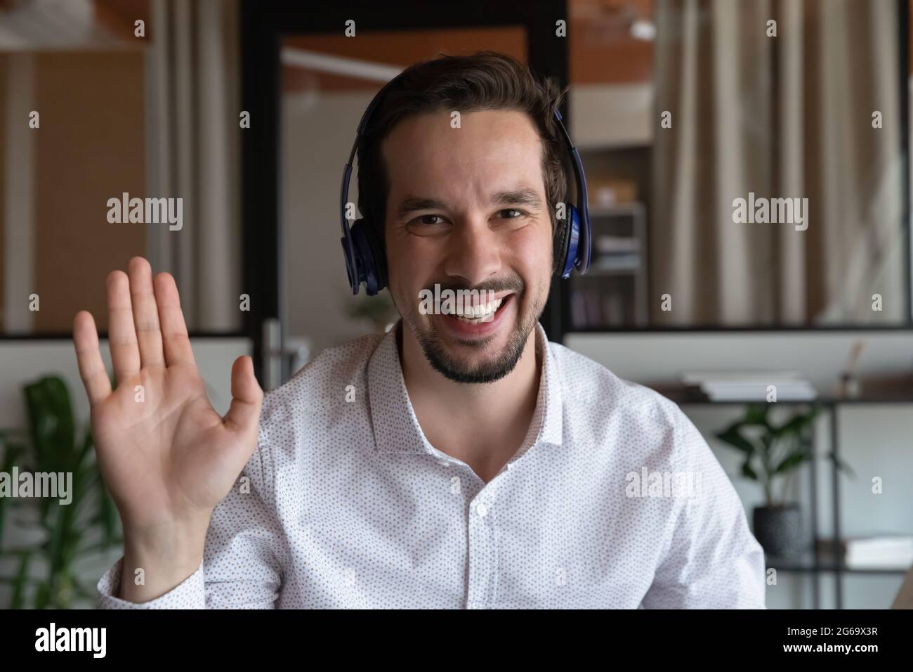 Porträt eines lächelnden Mannes in einem Kopfhörer, der die Hand schwenkt Stockfoto