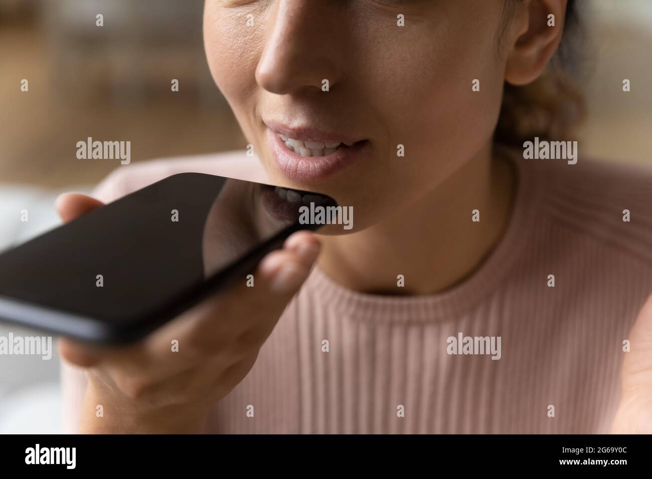 Junge hispanische Frau diktiert Audiobotschaft am Telefon. Stockfoto