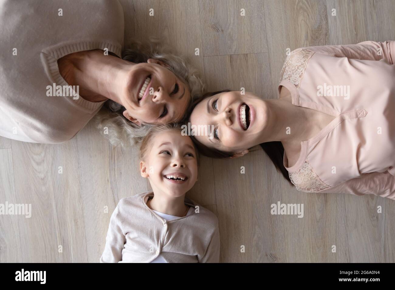 Drei verschiedene Frauen Tochter Mutter Großmutter lachend posiert auf dem Boden Stockfoto