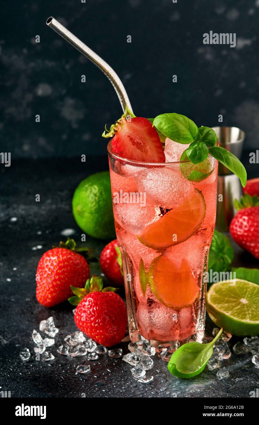 Glas Punsch und frische Zutaten für die Herstellung von Limonade, infundiert entgiftetes Wasser oder Cocktail. Erdbeeren, Limette, Minze, Basilikum, Eiswürfel und Shaker auf BL Stockfoto