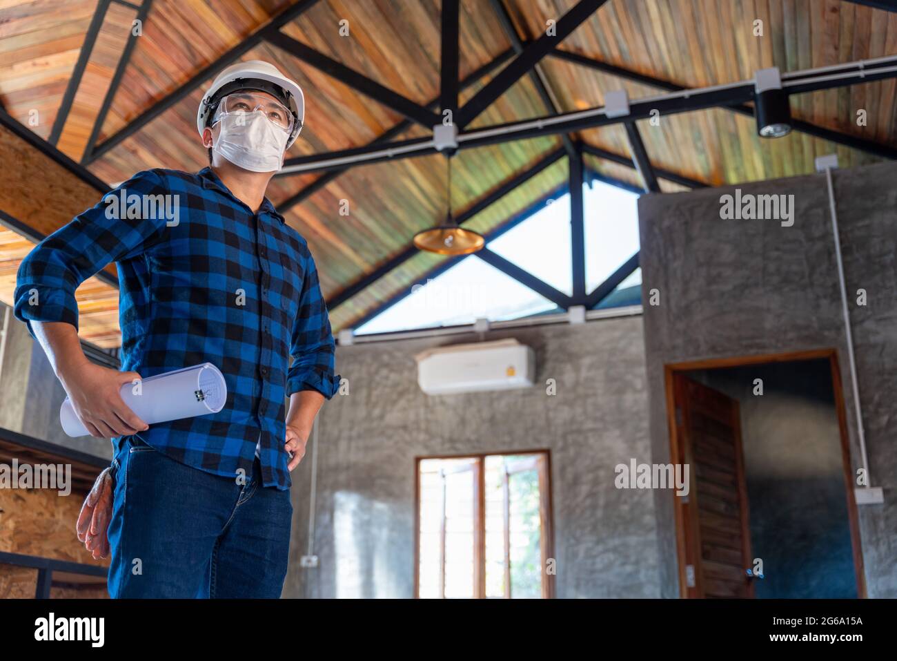 Glücklicher asiatischer Bauingenieur-Techniker nach der Inspektion der Holzstruktur unter dem Dach auf der Baustelle oder Baustelle eines Hauses. Stockfoto