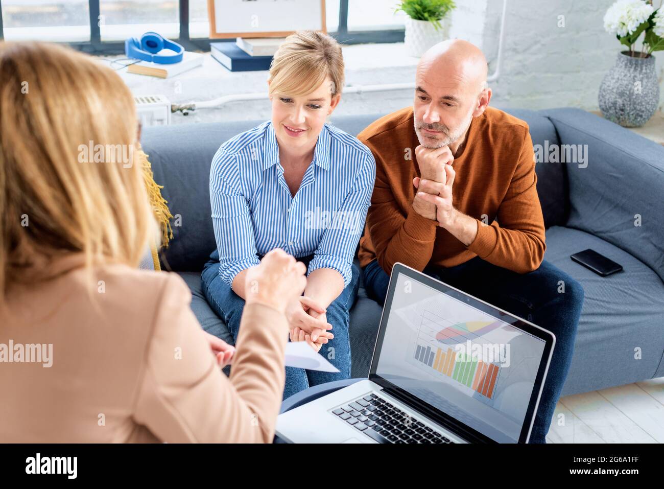 Glückliches Paar, das mit ihrem Finanzberater kommunizierte, während es zu Hause im Wohnzimmer saß. Stockfoto