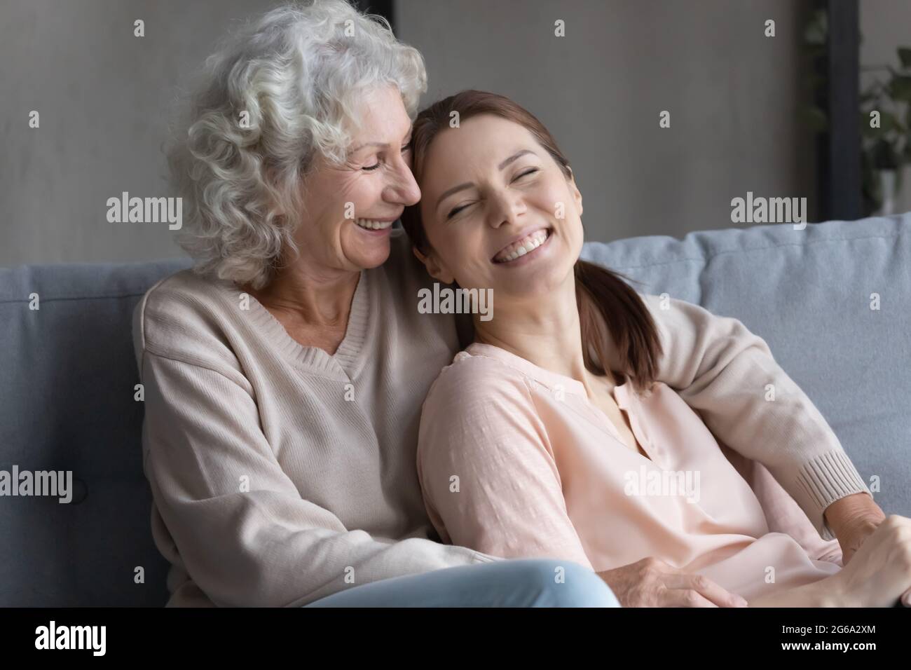 Lächelnde Frau erwachsenes Kind lehnt sich zurück zu älterer Mutter Stockfoto
