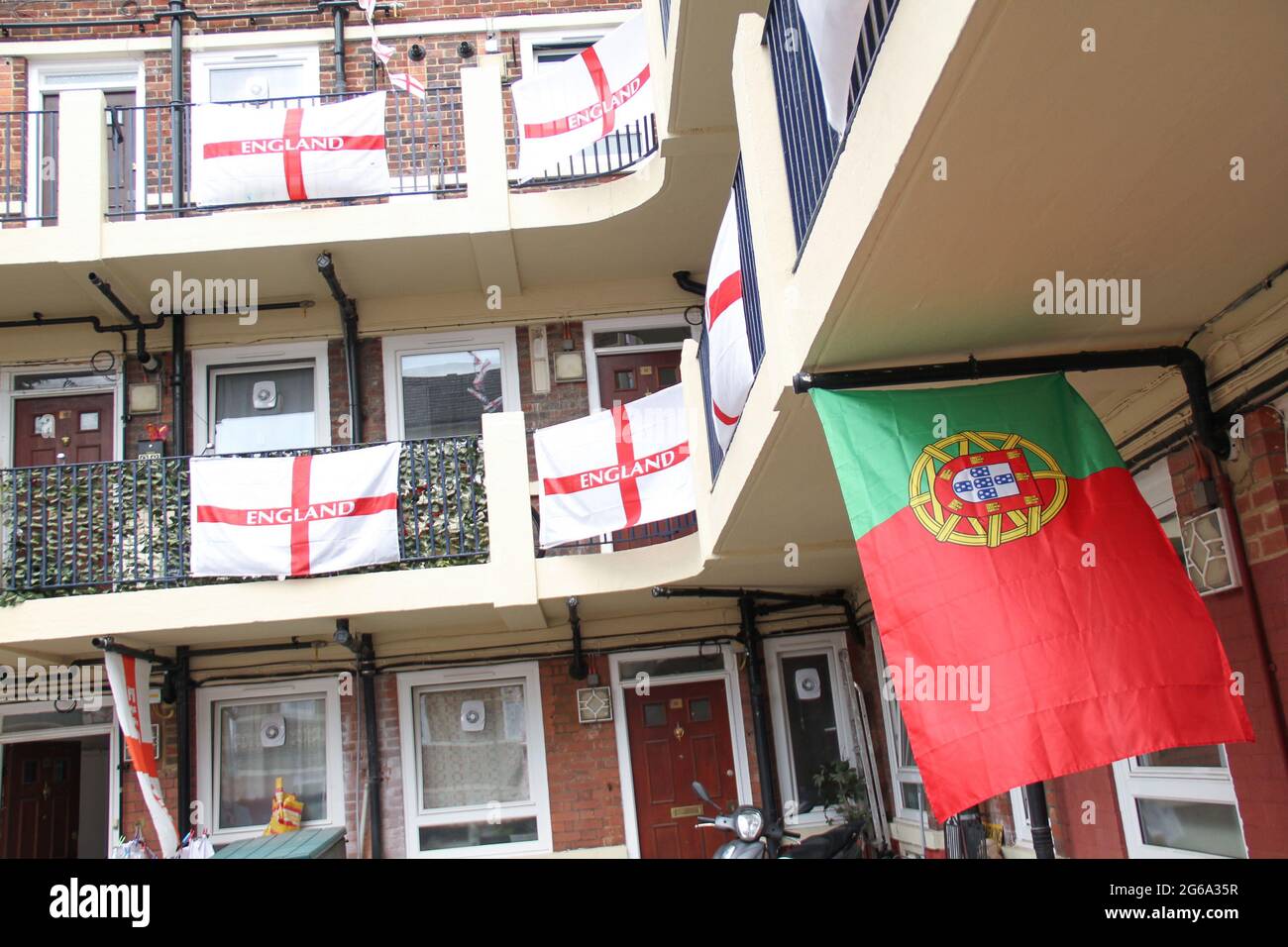 London, Großbritannien. Juli 2021. Eine portugiesische Flagge, die inmitten der mehr als 400 St George Flaggen zur Unterstützung der englischen Fußballmannschaft zu sehen ist.Kirby Estate in Bermondsey ist mit über 400 St George Flaggen zur Unterstützung der englischen Mannschaft für das verzögerte Euro 2020 Fußballturnier bedeckt. Eine Tradition der Gutsbewohner seit 2012.das englische Team besiegte die Ukraine 4-0 in Rom am 3. Juli und erreichte damit das Halbfinale gegen Dänemark, das am 6. Juli in Wembley angesetzt ist. (Foto von David Mbiyu/SOPA Images/Sipa USA) Quelle: SIPA USA/Alamy Live News Stockfoto
