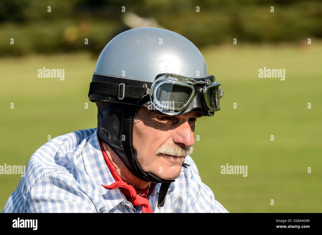 Älterer weißer Motorradfahrer mit Helm und Brille im Vintage-Stil, mit klassischem Schnurrbart. Älterer Motorradfahrer Stockfoto