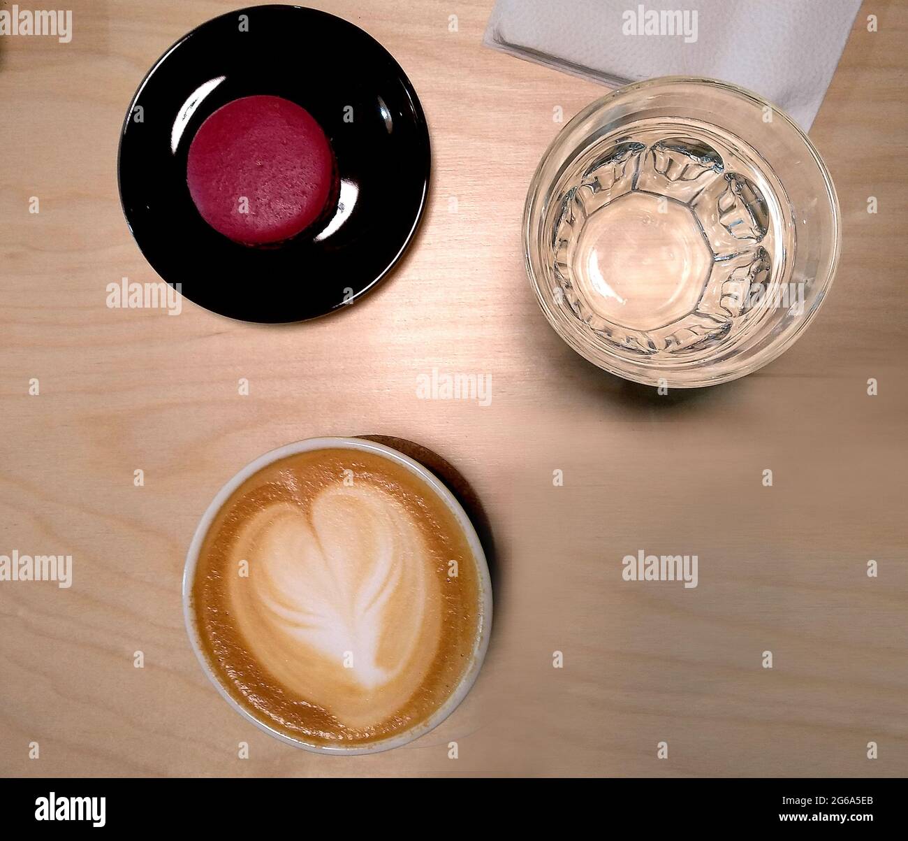 Ungewöhnlicher Kaffee Cappuccino mit Kuchen und Wasser im Café Stockfoto