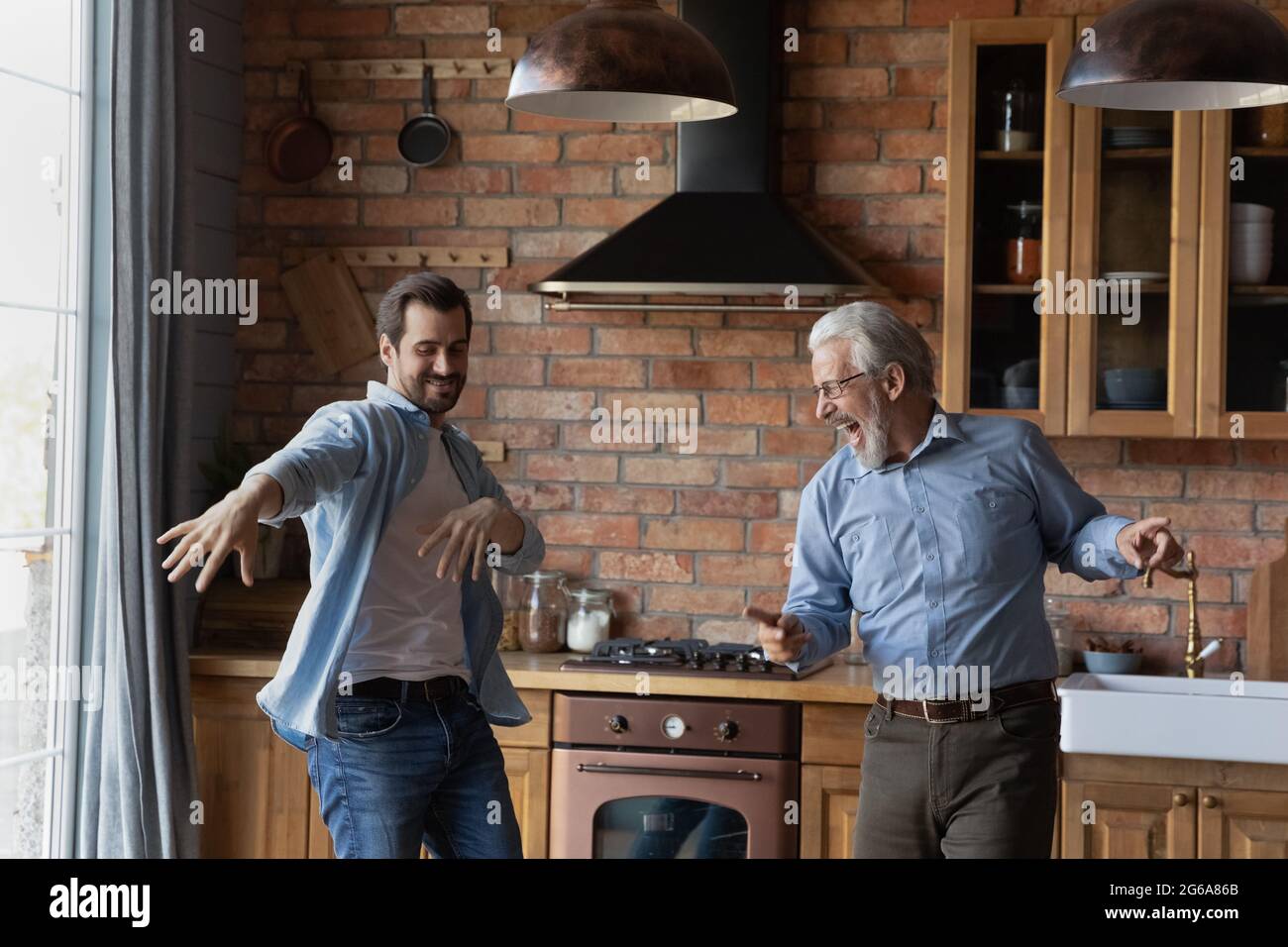 Aufgeregter erwachsener Sohn und älterer Vater, der Spaß in der Küche hat Stockfoto