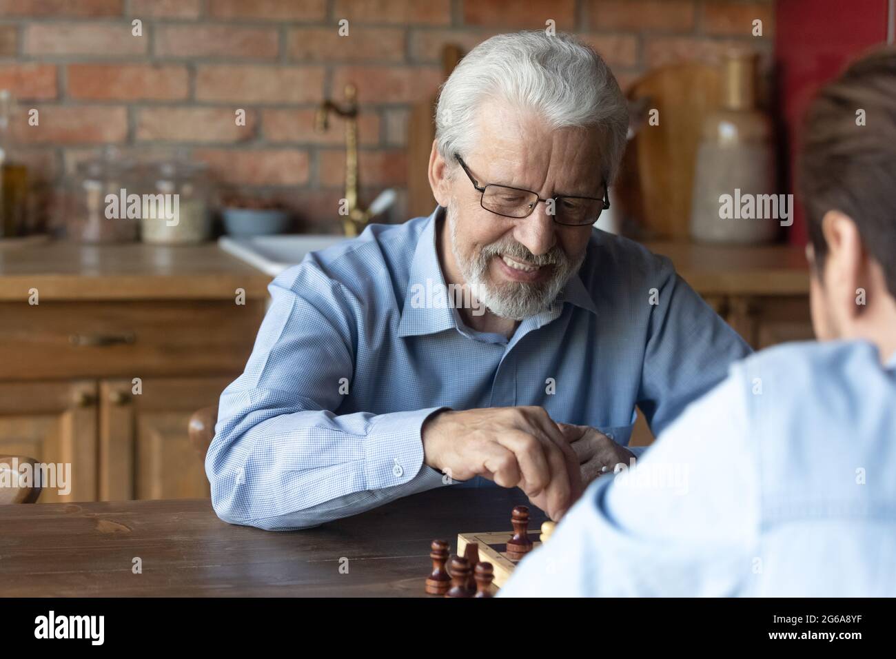 Glücklicher Vater aus den 70ern, der Schach spielt und mit dem erwachsenen Sohn spricht Stockfoto