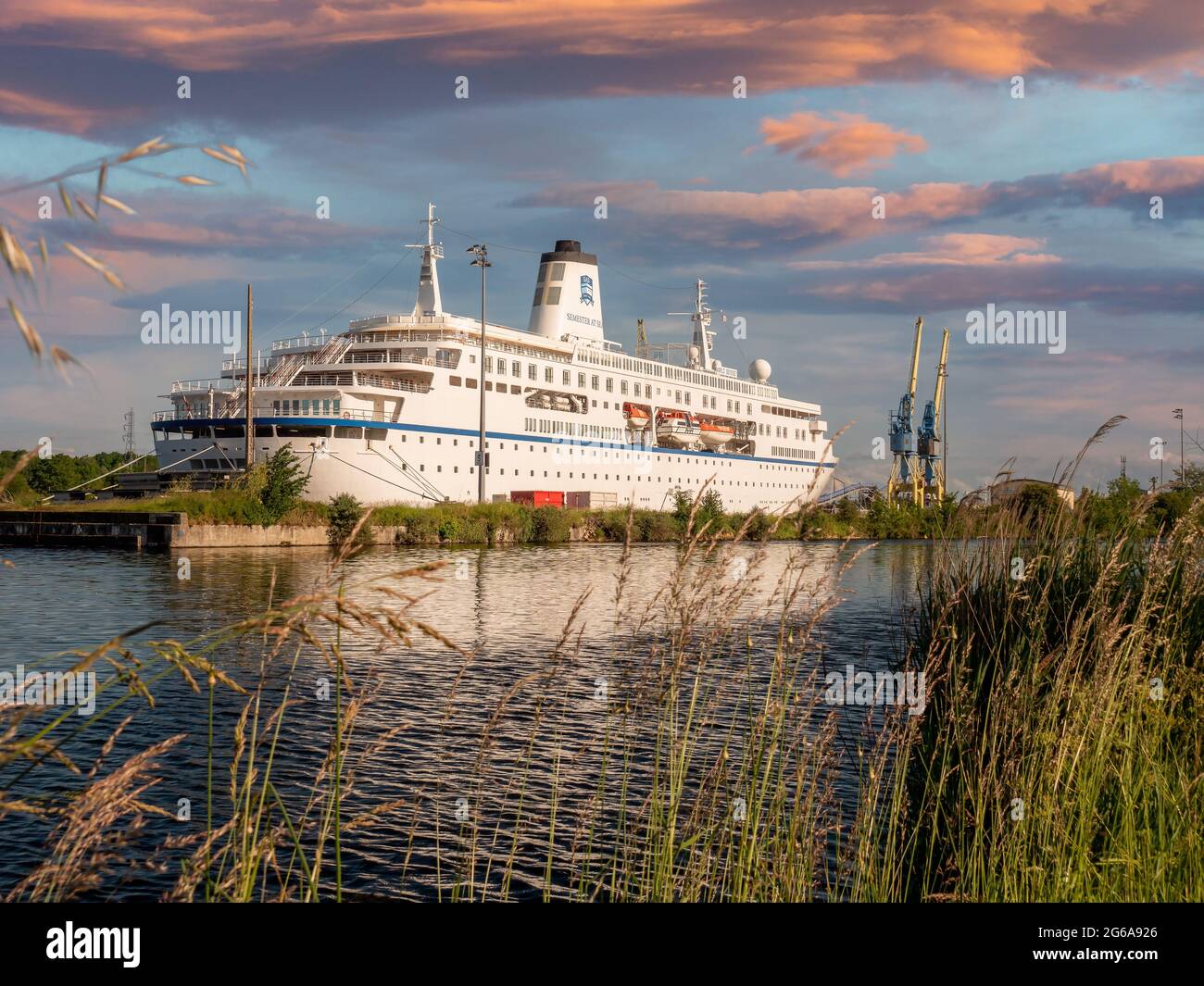 CAEN, FRANKREICH, JUNI 2021: Fähre World Odyssey in Canal de Caen Mer, schöner Himmel bei Sonnenuntergang, alter Betonsteg Stockfoto