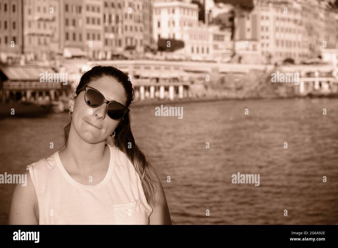 Ein junges Model in Sonnenbrillen an der Küste und am Strand von camogli, Ligurien, Italien. Mit den bunten Häusern im Hintergrund Stockfoto