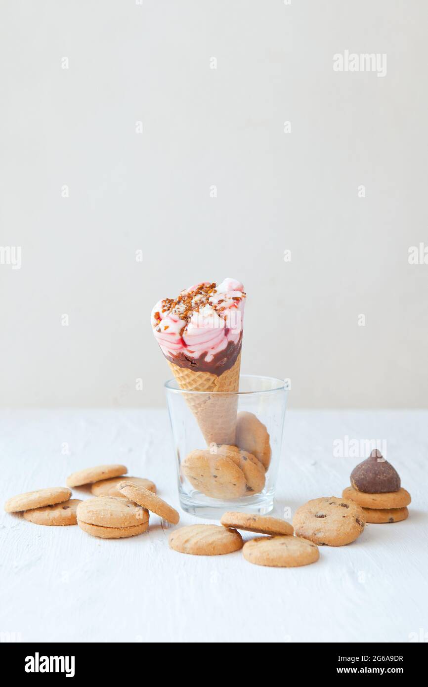 Waffelkegel mit leckerem Eis und Schokoladenkeksen auf dem Tisch. Eiskegel auf dem Glas mit Keksen Stockfoto