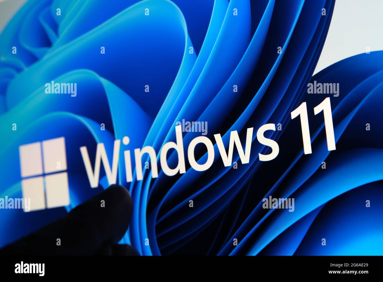 Windows 11-Logo auf dem Bildschirm des Tablets und Benutzer mit dem Finger auf sie zu sehen. Stafford, Großbritannien, 1. Juli 2021 Stockfoto