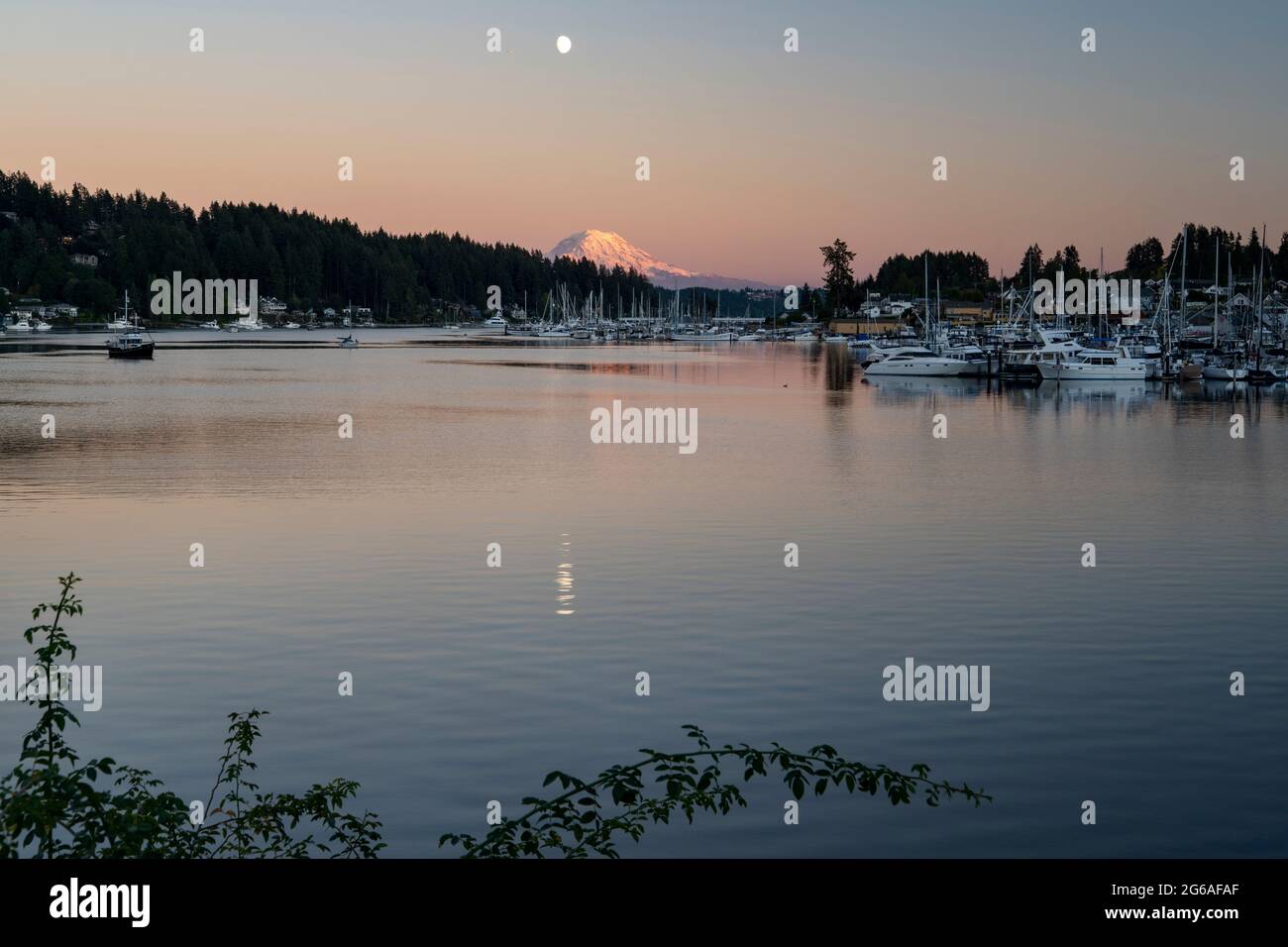 Erstaunlicher Mount Rainier und Mond, der sich über den Sonnenuntergang im Gig Harbour spiegelt Stockfoto