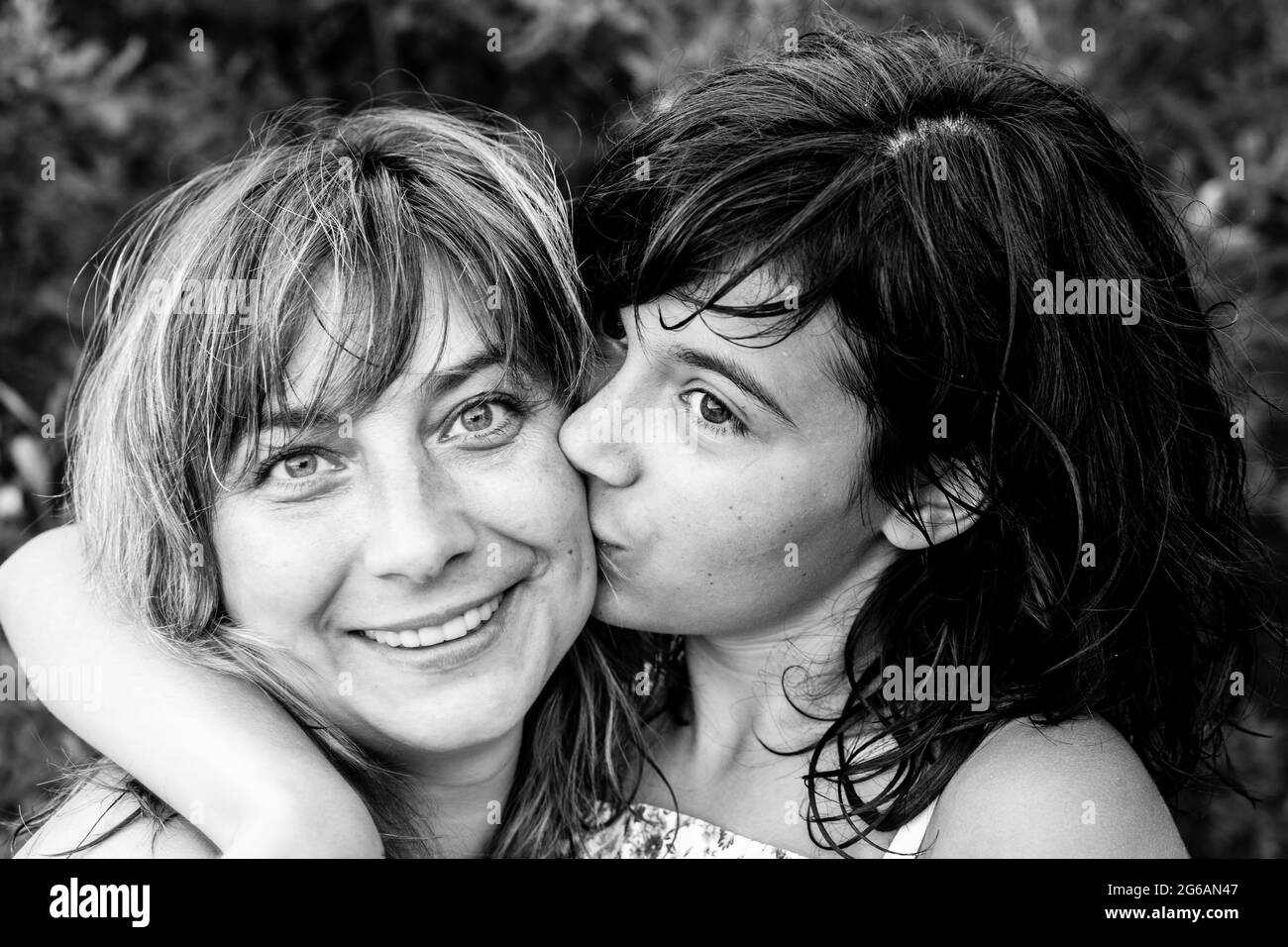 Eine Tochter im Teenageralter küsst ihre Mutter. Schwarzweiß-Foto. Stockfoto