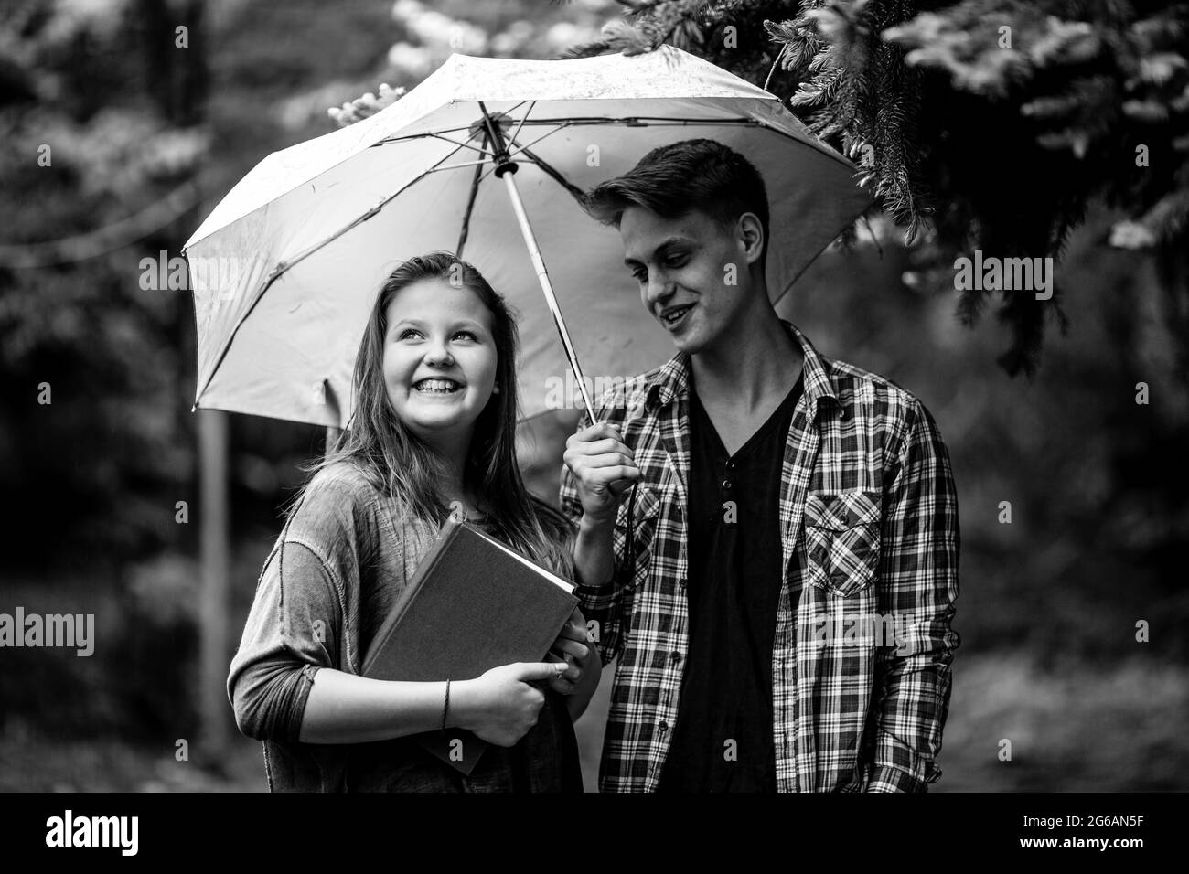 Ein junges Paar Studenten, ein Mann und ein Mädchen im Park unter einem Regenschirm. Schwarzweiß-Foto. Stockfoto