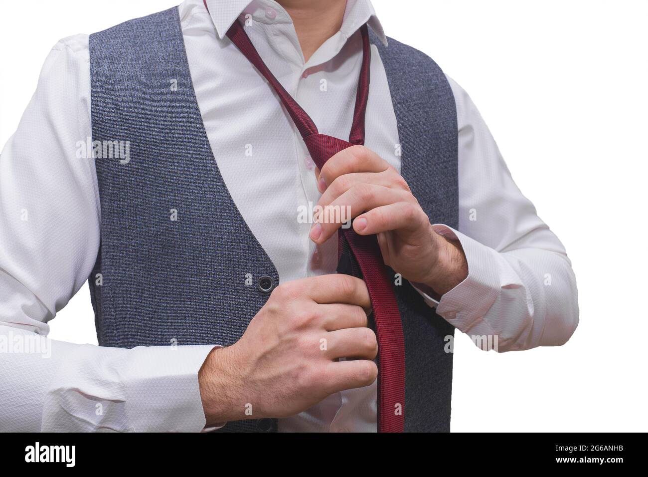 Die Hände des Mannes sind in einem weißen Hemd und einer grauen Weste mit einer roten Krawatte in Nahaufnahme gehalten. Stockfoto