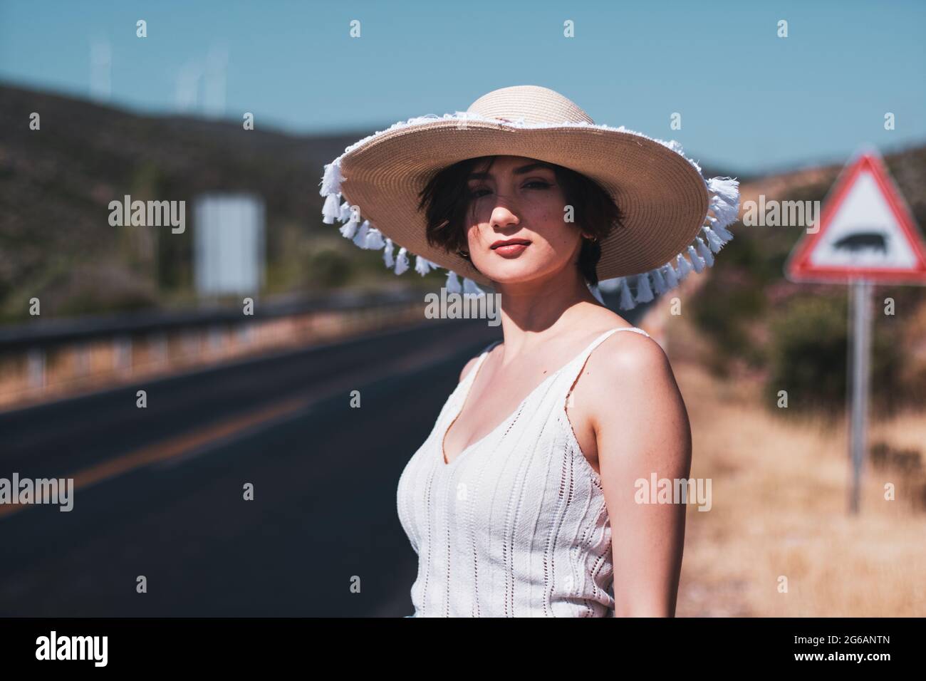 Porträt einer 20-jährigen Frau mit Strohhut, die am Straßenrand des Landes unterwegs ist Stockfoto