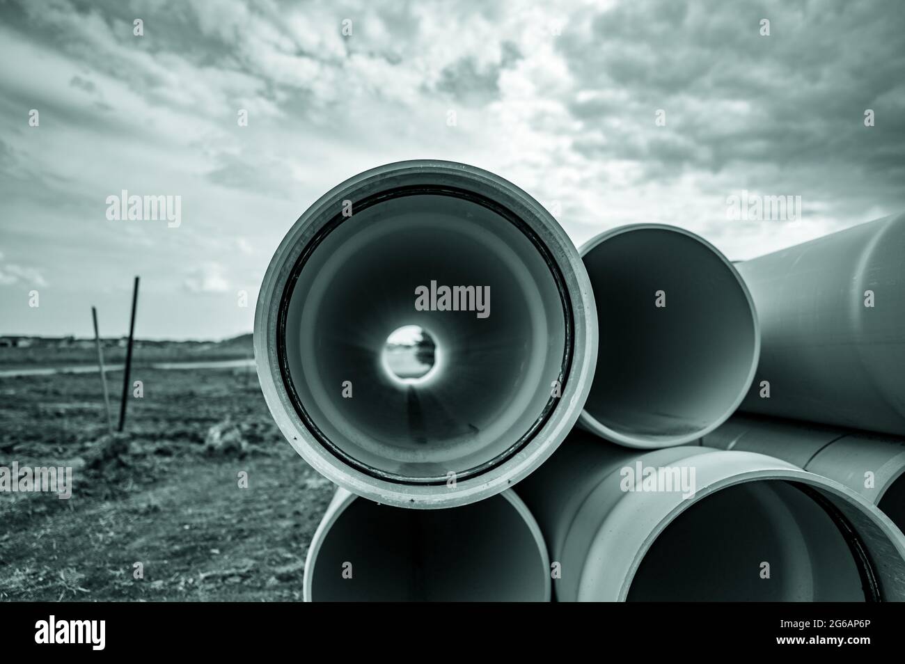 Gestapeltes Wasserhauptrohr mit Glockenanschluss neben einem freiliegenden Graben zur Installation Stockfoto