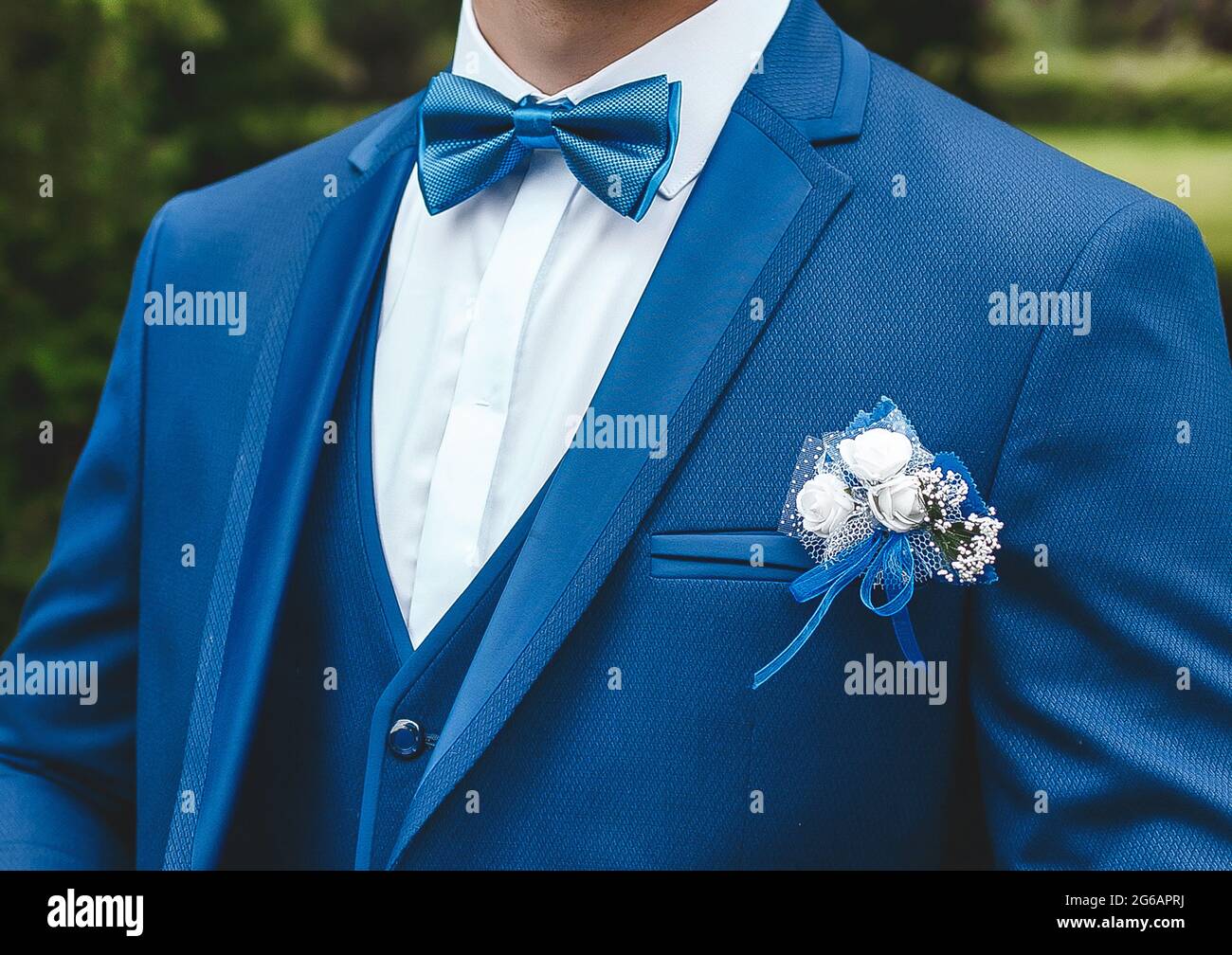 Ein Mann in einem weißen Hemd, einem blauen Anzug mit einem Schmetterling und einem Boutonniere, Nahaufnahme. Stockfoto