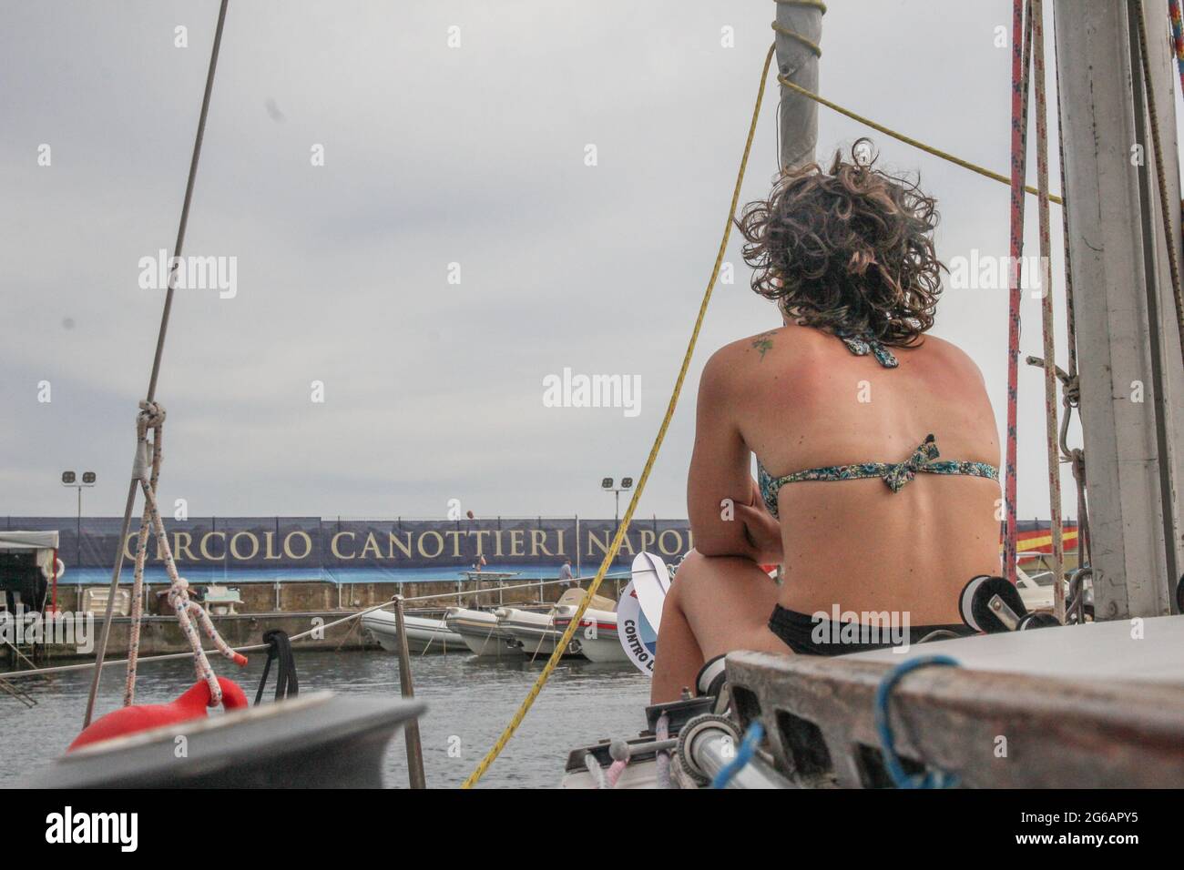 Golf von Neapel, Neapel, Italien, 4. Juli 2021. Boote treffen sich vor der Küste im Palazzo Donn'Anna zu einem nautischen Sturzmob gegen geschlechterspezifische Gewalt, der von der Naval League of Naples ins Leben gerufen wurde. Sie marschieren über Caracciolo, zeigen rote Bänder und senden mit Hörnern und Pfeifen akustische Signale aus. Die neapolitanische Mariafelicia Carraturo nimmt ebenfalls am Mob Teil, sie ist die Weltmeisterin des Freitauchens in variablem Gewicht mit Monoflosse. Sabrina Merolla/Alamy Stockfoto