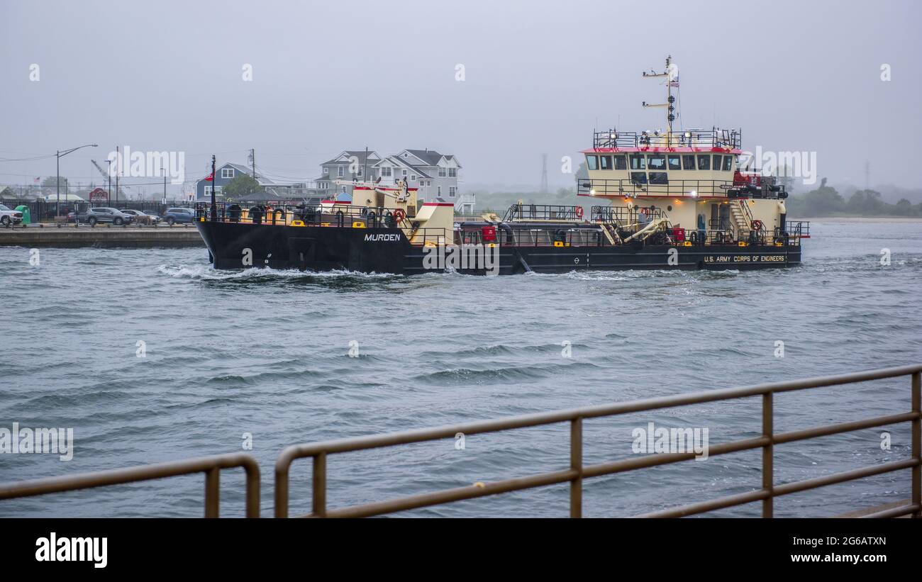 DAS US Army Corps of Engineers barge, das an einem bewölkten Tag aus dem Bay Outlet Manasquan, NJ, auf See fährt. Stockfoto DAS US Army Corps of Engineers barge, das an einem bewölkten Tag aus dem Bay Outlet Manasquan, NJ, auf See fährt. Stockfoto