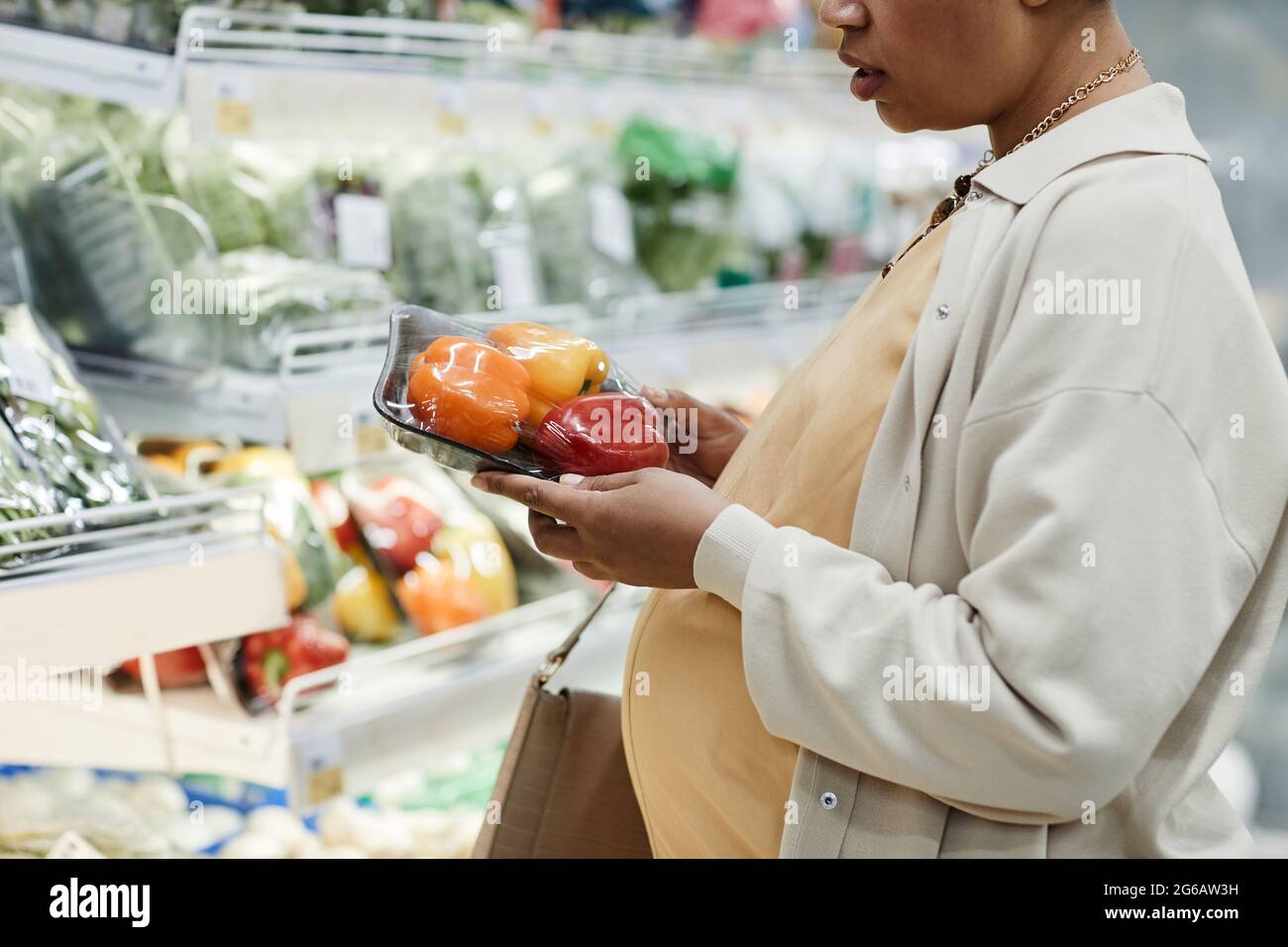 Verkürzte Seitenansicht Porträt einer schwanger afroamerikanischen Frau, die beim Einkaufen im Supermarkt Lebensmittel kauft Stockfoto