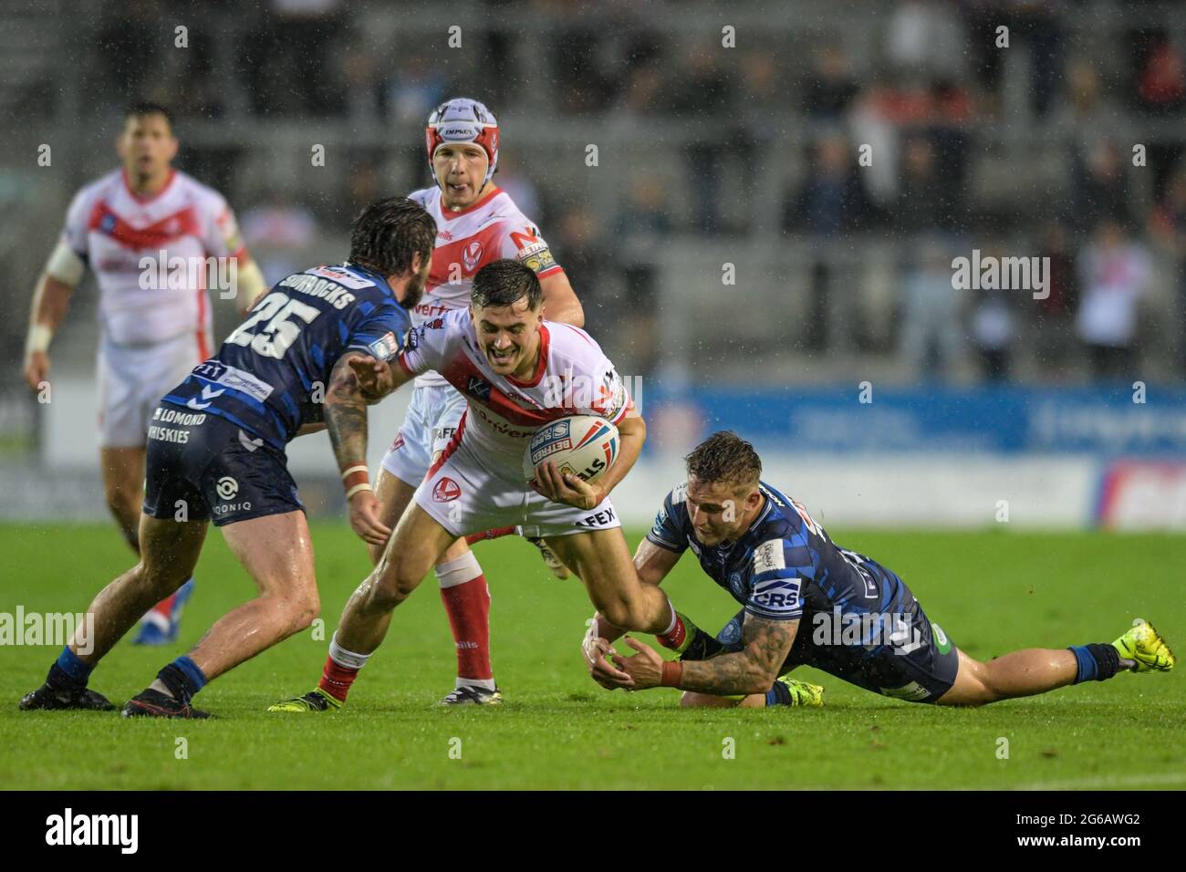 Lewis Dodd (21) von St. Helens wird von Sam Powell (9) von Wigan Warriors und Joe Shorrocks (25) von Wigan Warriors angegangen Stockfoto