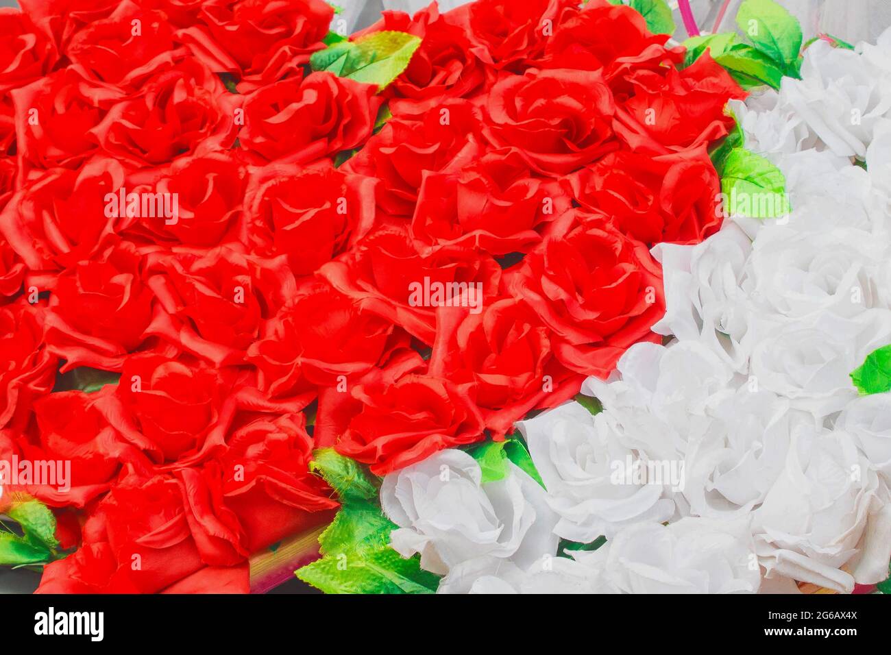 Herz aus roten künstlichen Rosen gegenüber weißen unbelebten Hintergrund Blumen. Stockfoto