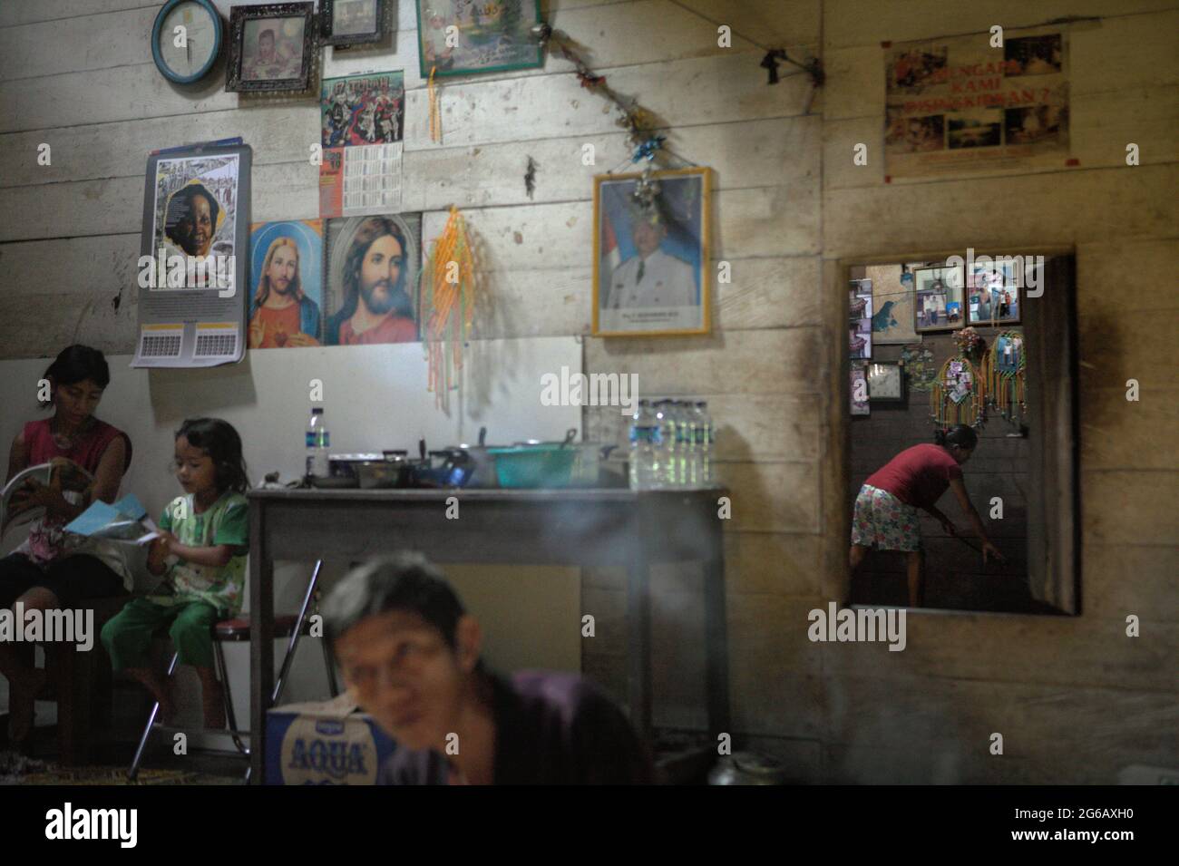 Sie haben bereits einen schlechten Zugang zur Gesundheitsversorgung, deutlich höhere Raten übertragbarer und nicht übertragbarer Krankheiten, fehlenden Zugang zu grundlegenden Dienstleistungen, Sanitäreinrichtungen und andere wichtige Präventivmaßnahmen zu spüren; Laut dem Wirtschafts- und Sozialministerium der Vereinten Nationen stehen die indigenen Völker weltweit vor einer ernsten Gesundheitsbedrohung, die durch die Covid-19-Pandemie ausgeht. Auf diesem Foto lesen eine Frau und ein Kind, während Raimundus Remang, der Leiter des Siedlungsgebiets, den Besuchern im Langhaus der traditionellen Dayak IBAN-Gemeinde in Sungai Utik die Dinge erklärt. Stockfoto