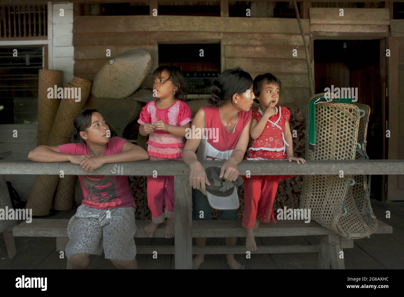Sie haben bereits einen schlechten Zugang zur Gesundheitsversorgung, deutlich höhere Raten übertragbarer und nicht übertragbarer Krankheiten, fehlenden Zugang zu grundlegenden Dienstleistungen, Sanitäreinrichtungen und andere wichtige Präventivmaßnahmen zu spüren; Laut dem Wirtschafts- und Sozialministerium der Vereinten Nationen stehen die indigenen Völker weltweit vor einer ernsten Gesundheitsbedrohung, die durch die Covid-19-Pandemie ausgeht. Auf diesem Foto erklären Frauen Kindern im Langhaus der traditionellen Dayak IBAN-Gemeinde in Sungai Utik, West Kalimantan, Indonesien, Dinge. © Reynold Sumayku Stockfoto