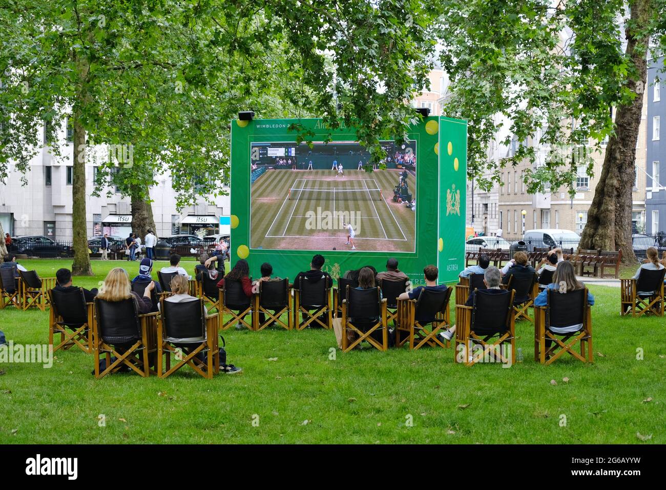 Die Menschen genießen öffentliche Vorführungen des Wimbledon-Tennisturniers auf dem Berkerley Square in Mayfair, als einer von vielen Outdoor-Bildschirmen in der Hauptstadt Stockfoto