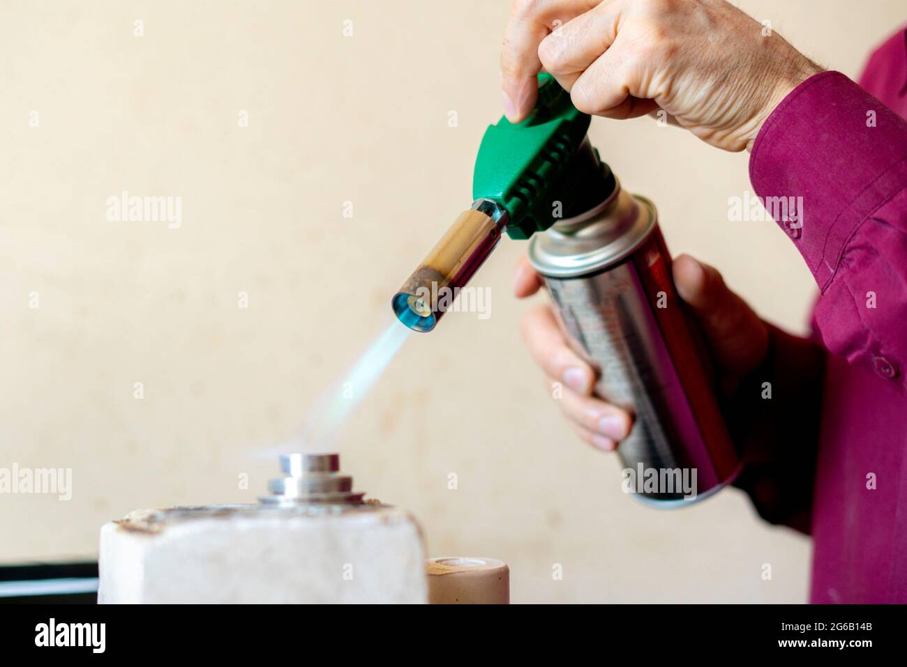 Die Hände eines Arbeiters benutzen einen Gasbrenner in einer Werkstatt Stockfoto