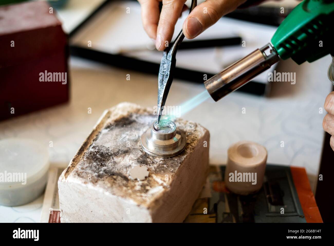 Die Hände eines Arbeiters benutzen einen Gasbrenner in einer Werkstatt Stockfoto
