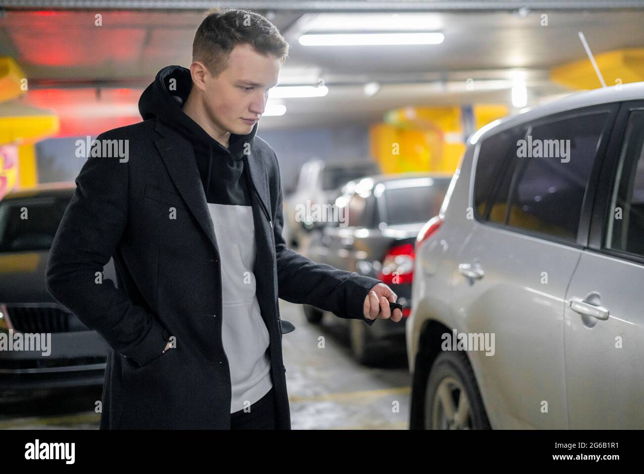 Mann öffnet sein Auto in der Tiefgarage Stockfoto