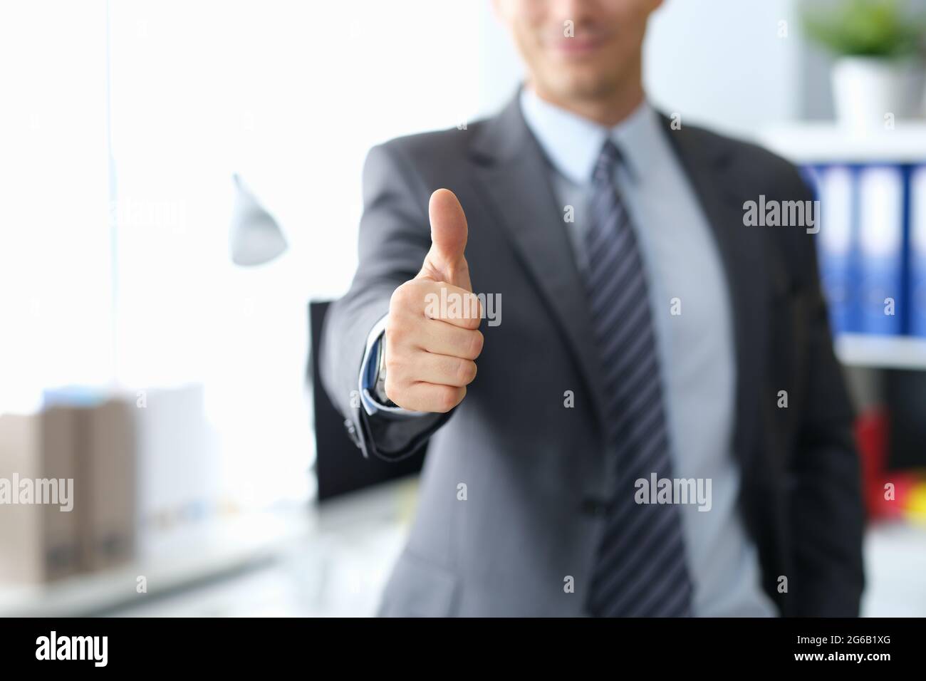 Geschäftsmann zeigt Daumen nach oben, während er im Büro steht Stockfoto