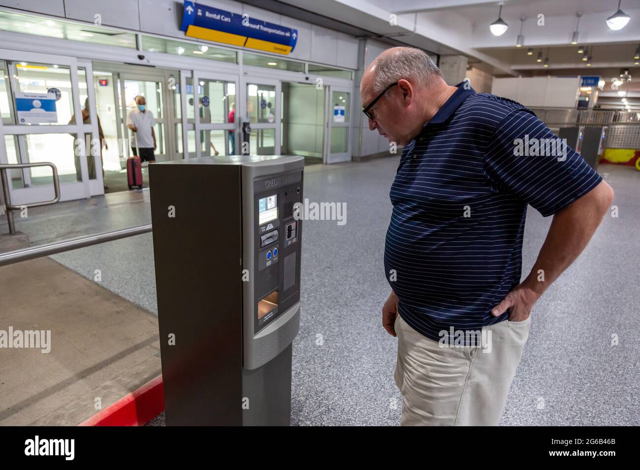 Ein Mann bereitet sich darauf vor, für das Parken an einem Kiosk in einer Parkgarage am internationalen Flughafen Indianapolis in Indy zu bezahlen. Stockfoto