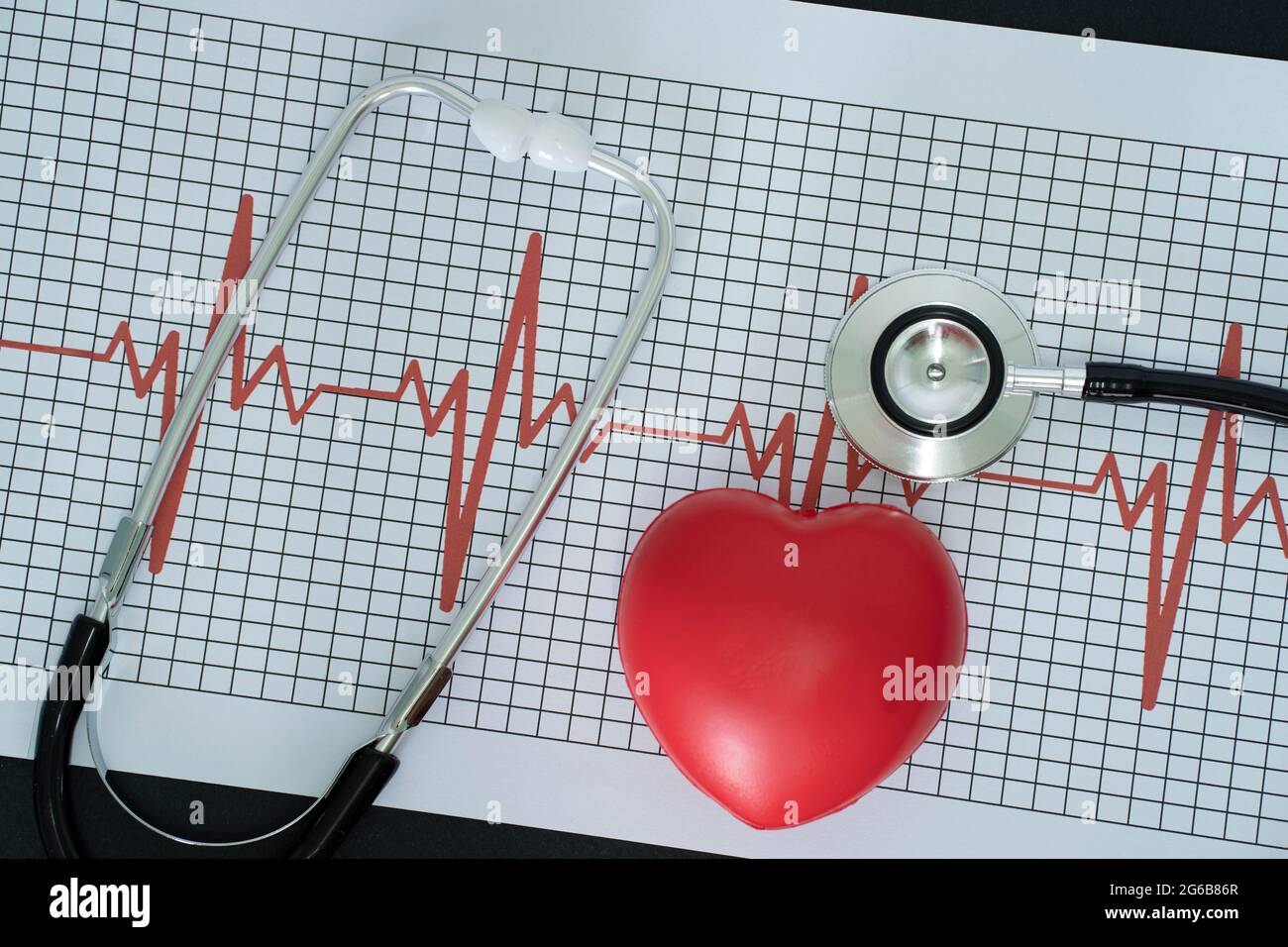 Aufbau eines Elektrokardiogramms, Stethoskops und eines herzförmigen Modells auf schwarzem Hintergrund Stockfoto