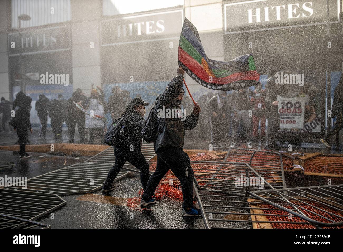 Santiago, Chile. Juli 2021. Ein Mann hält eine Mapuche-Flagge, als eine Gruppe von Demonstranten während der Demonstration mit der Bereitschaftspolizei konfrontiert wird.Demonstranten versammelten sich am ersten Tag der Verfassungsversammlung in der Nähe des ehemaligen Nationalkongresses. Kredit: SOPA Images Limited/Alamy Live Nachrichten Stockfoto