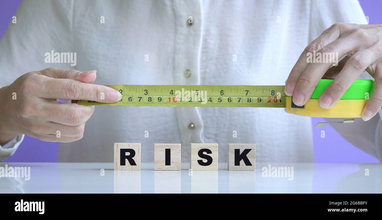 Geschäftsfrau mit gelbem Maßband auf Risikowürfeln aus Holz. Stockfoto