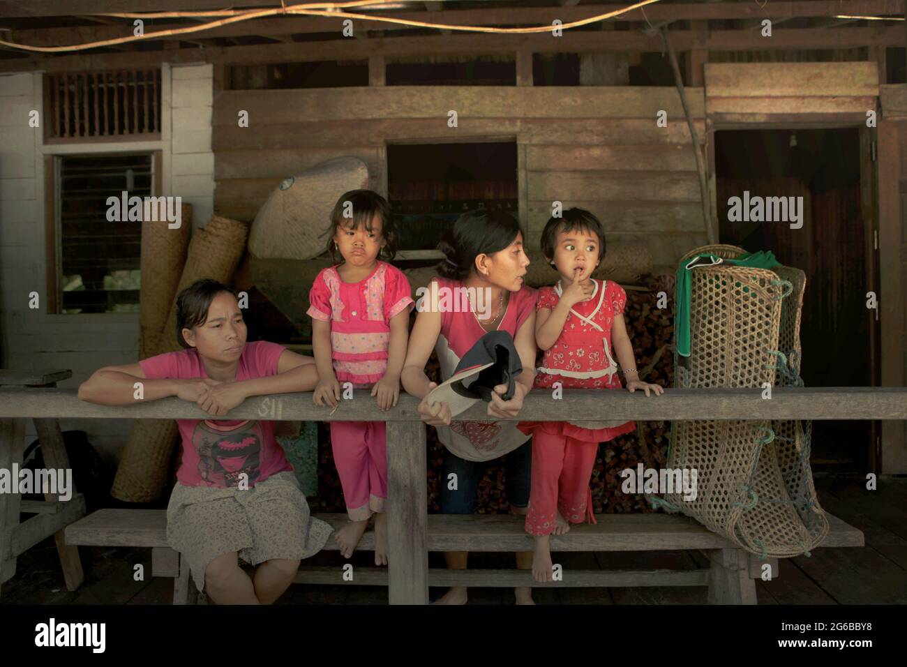 Frauen erklären Kindern im Langhaus der traditionellen Dayak IBAN-Gemeinde in Sungai Utik, West Kalimantan, Indonesien, Dinge. Die Auswirkungen des Klimawandels sind nicht geschlechterneutral, da Frauen und Kinder zu den höchsten Risikogruppen gehören, so ein wissenschaftliches Dokument aus dem Jahr 2021, das sich auf Klimarisiken konzentriert und von der Weltbank-Gruppe und der Asiatischen Entwicklungsbank veröffentlicht wurde. „Frauen und Kinder benötigen soziale Unterstützung, um ihre Gesundheit und ihr Wohlbefinden sowie die ihrer Kinder zu fördern“, schrieb ein Wissenschaftlerteam unter der Leitung von Emily H Emmott in einem von der Royal Society veröffentlichten Forschungsbericht. Stockfoto