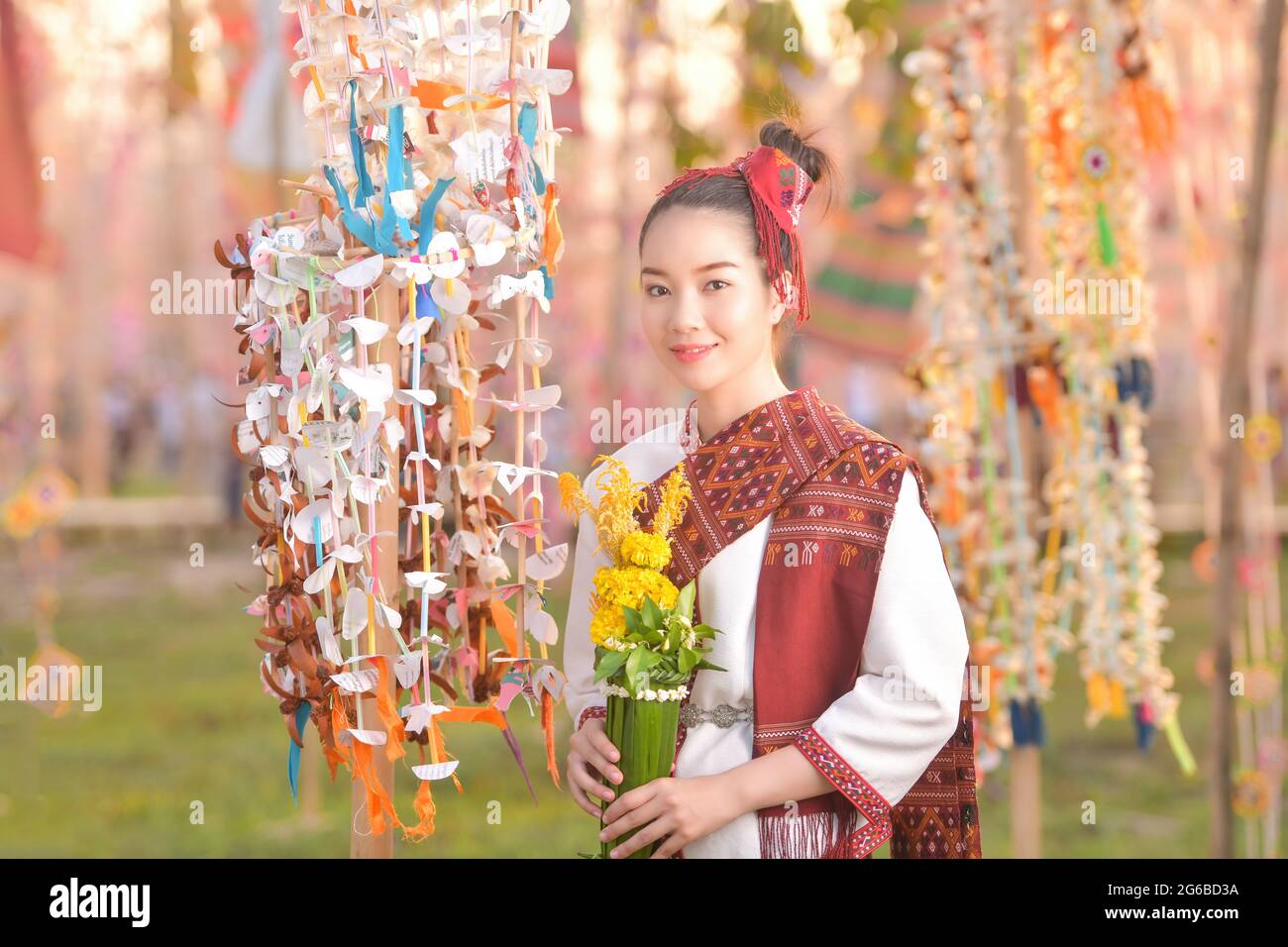 Porträt einer lächelnden Frau in traditioneller thailändischer Kleidung mit Blumen, Thailand Stockfoto