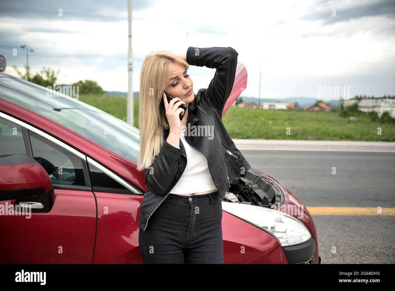 Porträt einer Frau, die an einem abgebrochenen Auto steht und auf ihrem Mobiltelefon spricht, Bosnien und Herzegowina Stockfoto
