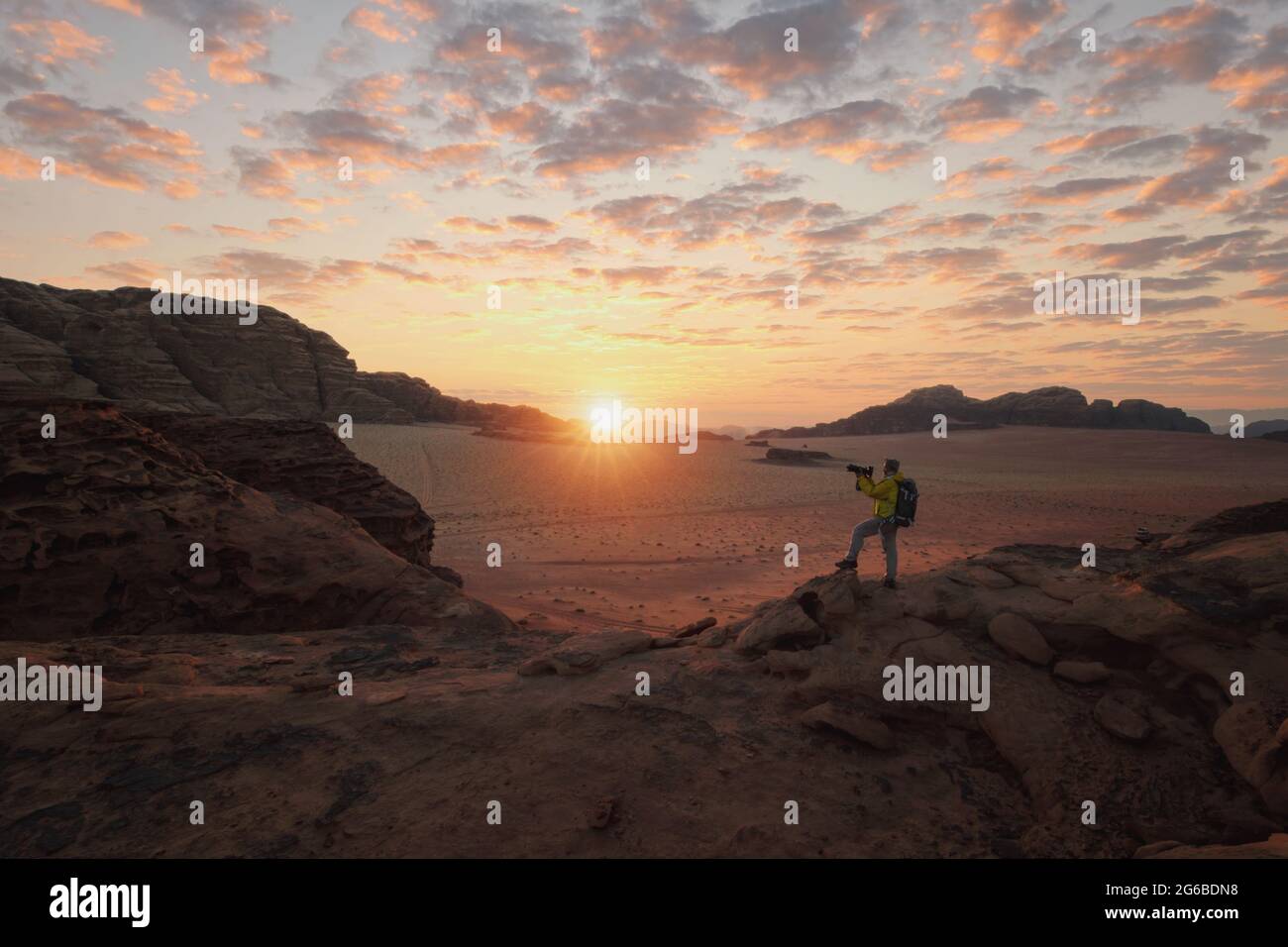Mann, der in der Wüste steht und bei Sonnenuntergang Fotos macht, Wadi Rum, Jordanien Stockfoto